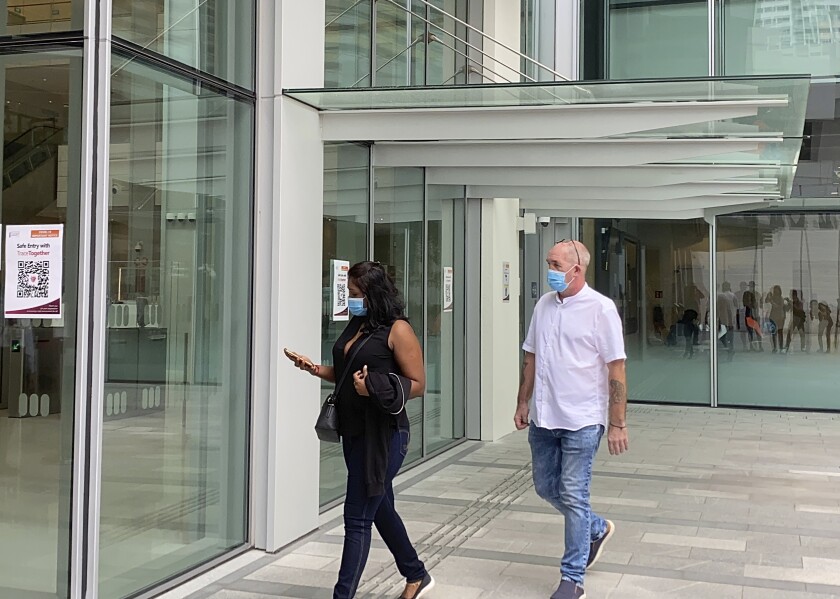 Agatha Maghesh Eyamalai, left, and Skea Nigel walk into the State Courts in Singapore, Monday, Feb. 15, 2021. The Briton man pleaded guilty on Monday to violating a coronavirus quarantine order in Singapore to visit his fiancee. (AP Photo/Annabelle Liang)