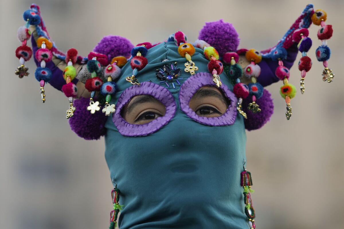 A costumed demonstrator joins in performing the feminist anthem, "A rapist in your path", during a demonstration against gender-based violence, one day ahead of International Women's Day in Santiago, Chile, Monday, March 7, 2022. The anthem has been adopted by activists across the world to denounce violence against women since first being performed in Chile during a wave of anti-government protests in 2019. (AP Photo/Esteban Felix)