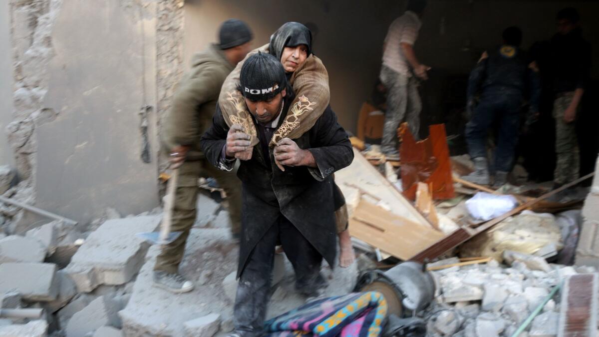 A Syrian rescuer carries a woman from the rubble of a building after reported airstrikes on a rebel-held district in Aleppo on Sunday.