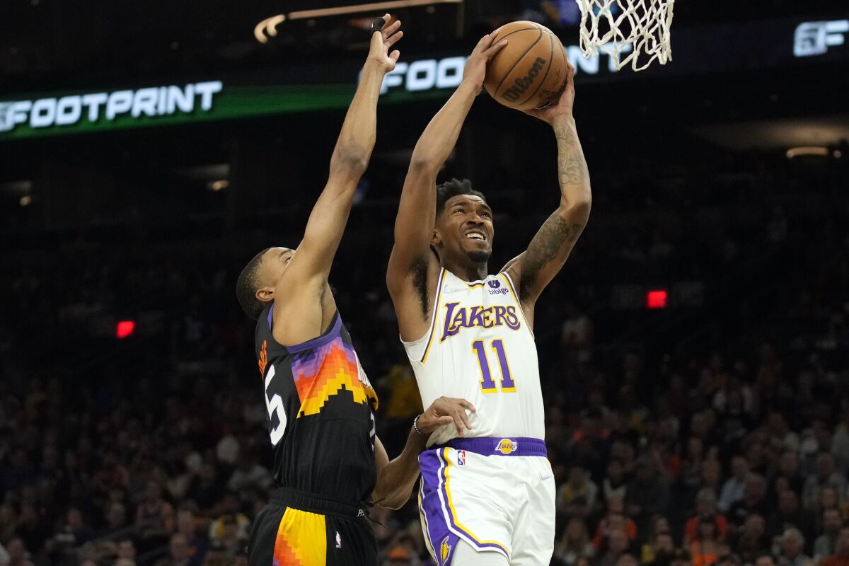 Lakers guard Malik Monk elevates past Suns forward Mikal Bridges on a drive to the basket.