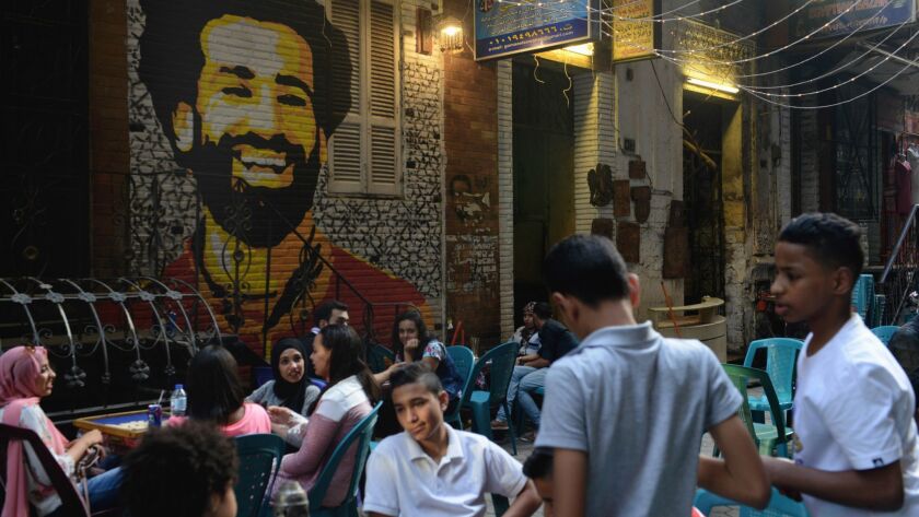 Egyptian soccer fans sit in front of a mural of star forward Mohamed Salah at a cafe in downtown Cairo after the Egypt-Uruguay match, the country's first World Cup match in 28 years.