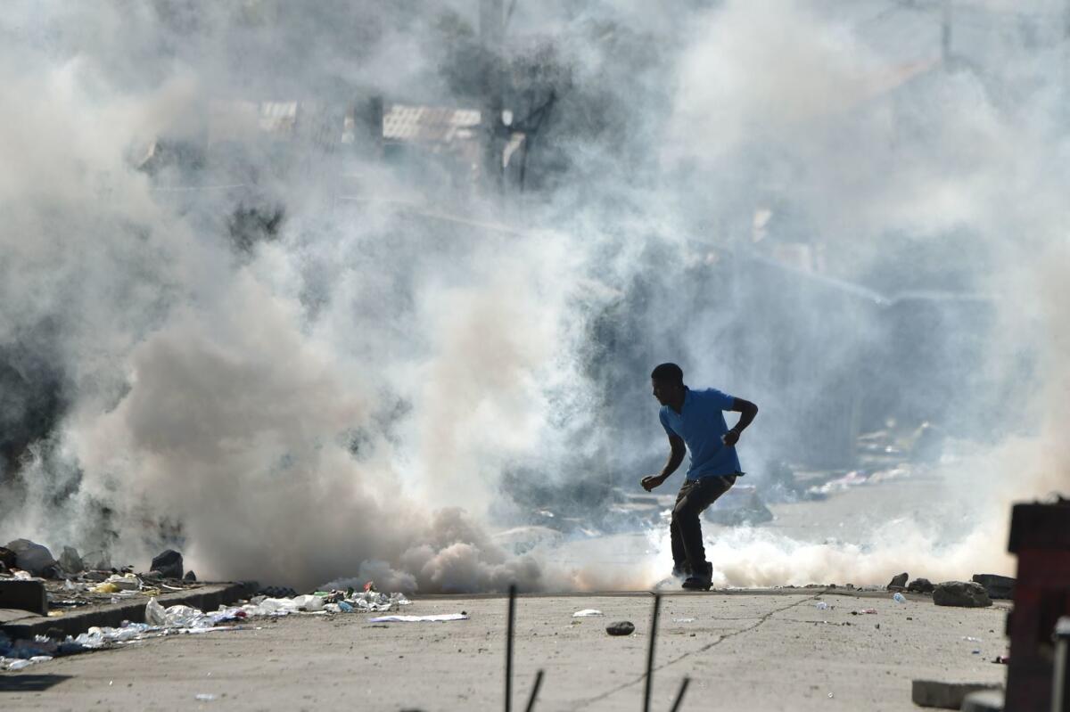 A man kicks a tear-gas canister fired by police during clashes in the Haitian capital, Port-au-Prince, on Nov. 29, 2016.