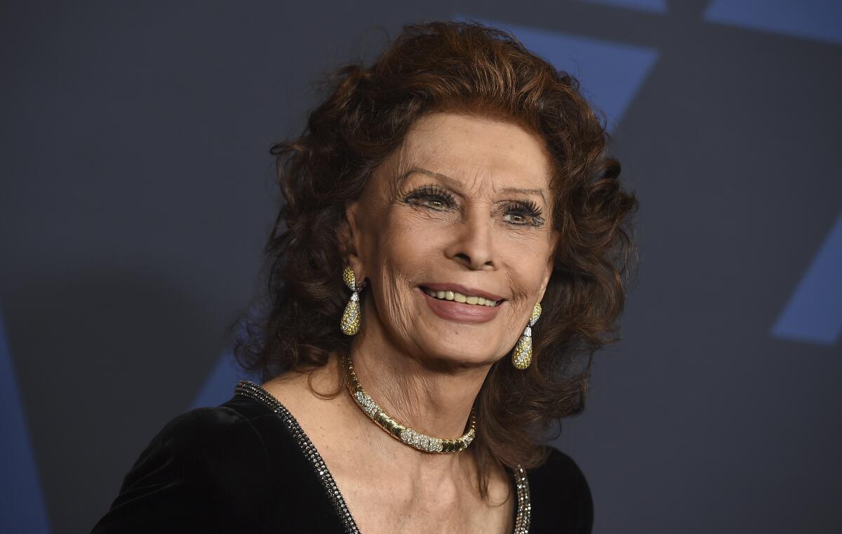 Sophia Loren wears a black dress while posing for photos at a red carpet event
