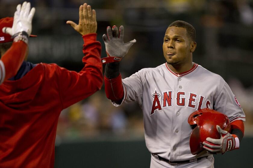 Erick Aybar is congratulated by his teammates after scoring a run against Oakland in the second inning. The Angels beat the Athletics, 2-0.