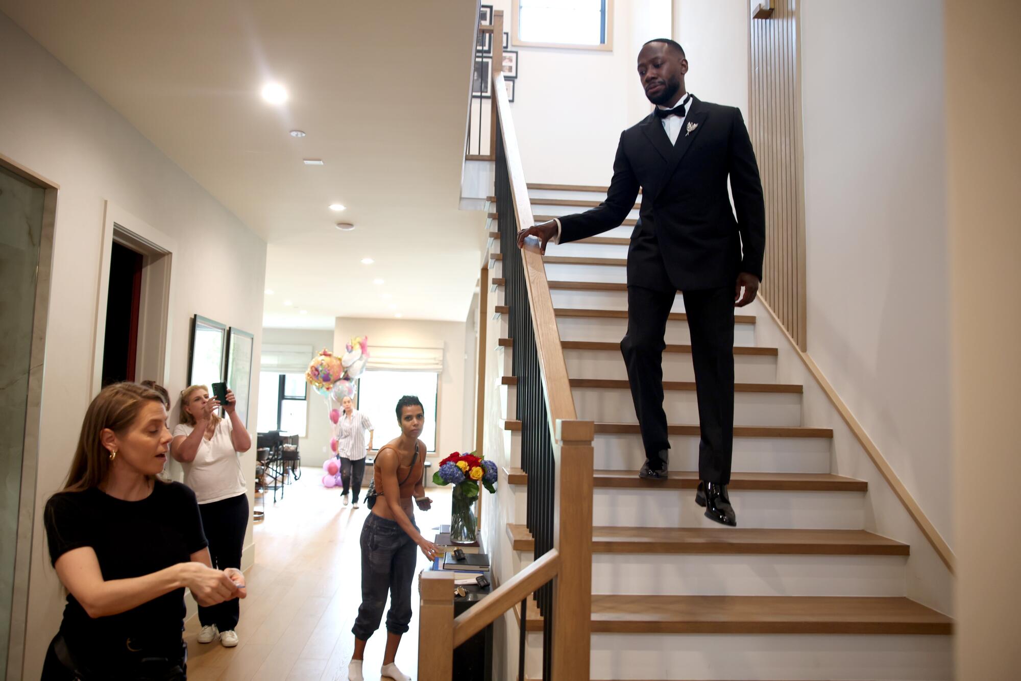 A man in a tuxedo walks down stairs.