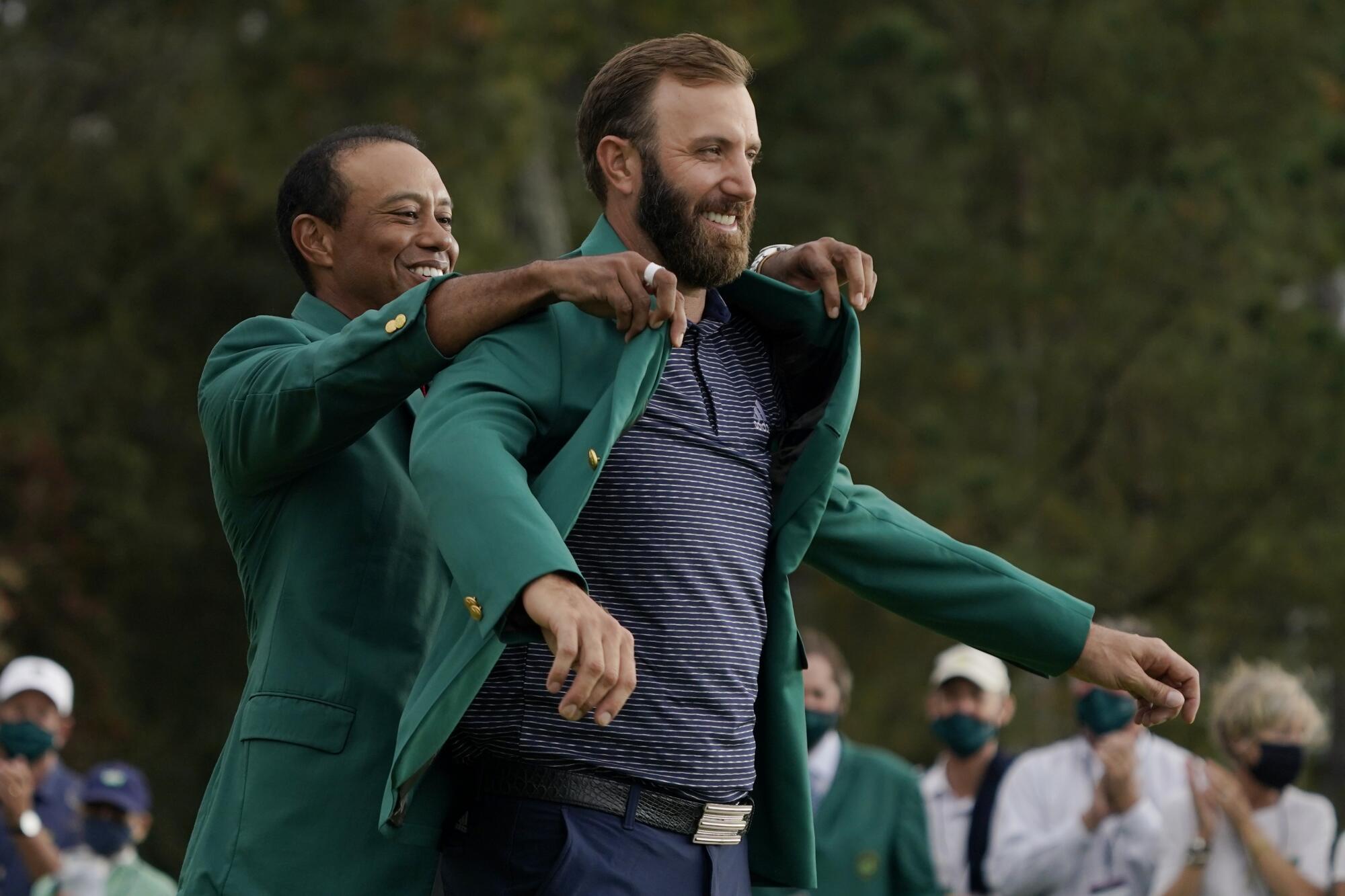 Tiger Woods helps Masters' champion Dustin Johnson with his green jacket after his victory at the Masters in 2020.