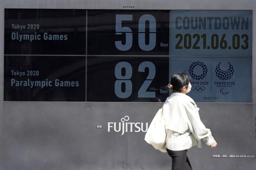 People walk past the countdown clock for the Tokyo 2020 Olympic and Paralympic Games near Shimbashi station in Tokyo, Thursday, June 3, 2021, to mark 50 days before the start of the Summer Games. (AP Photo/Kantaro Komiya)