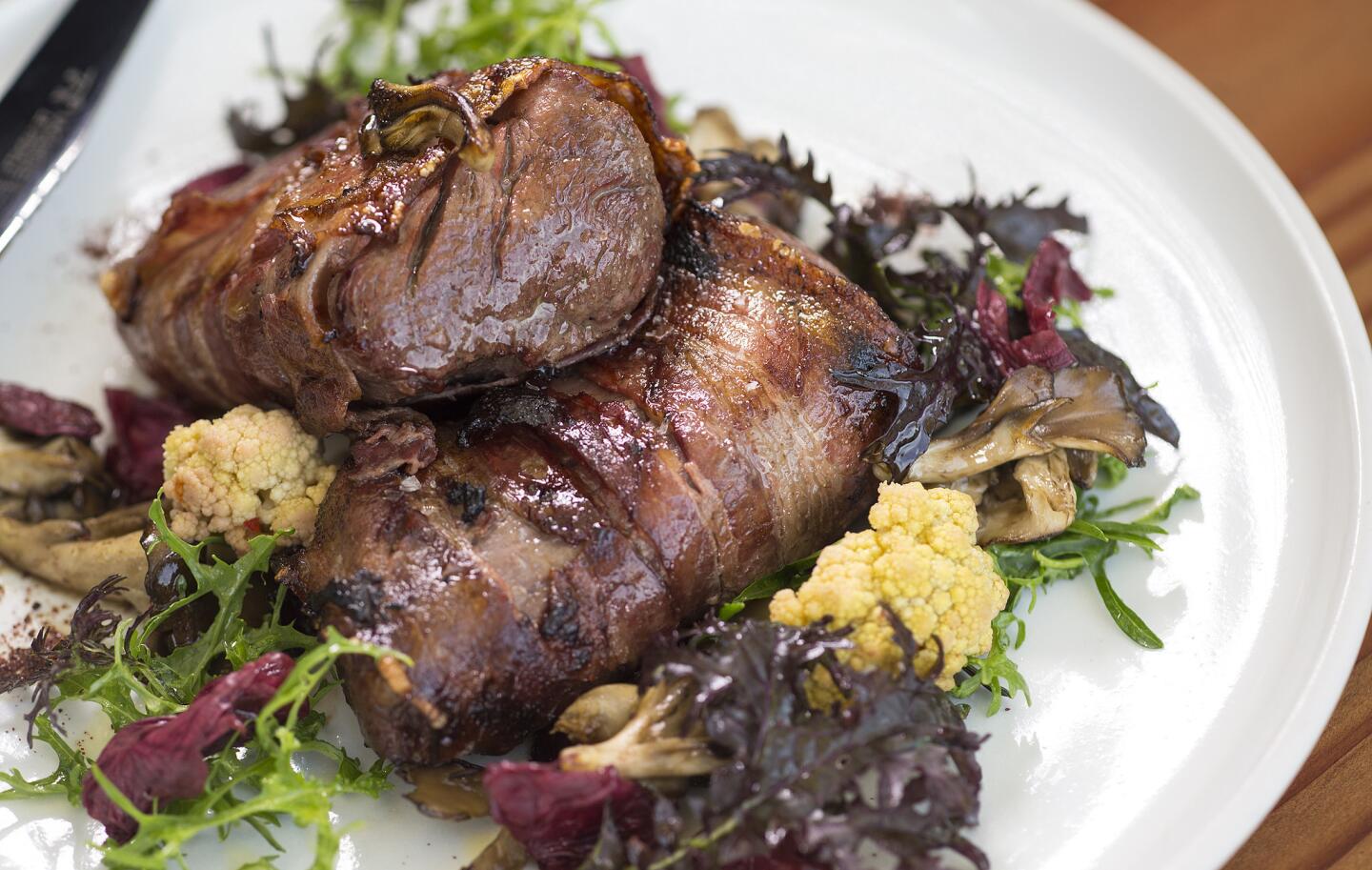 The bacon-wrapped elk loin is served with maitake and fermented radicchio at Manuela.