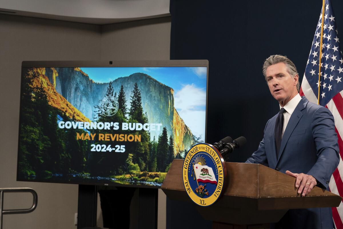 California Gov. Gavin Newsom stands next to a video display