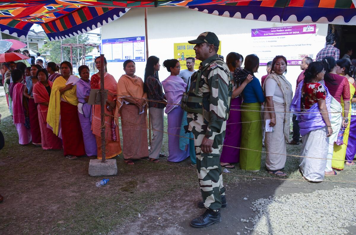 A soldier stands guard as women queue up to vote.