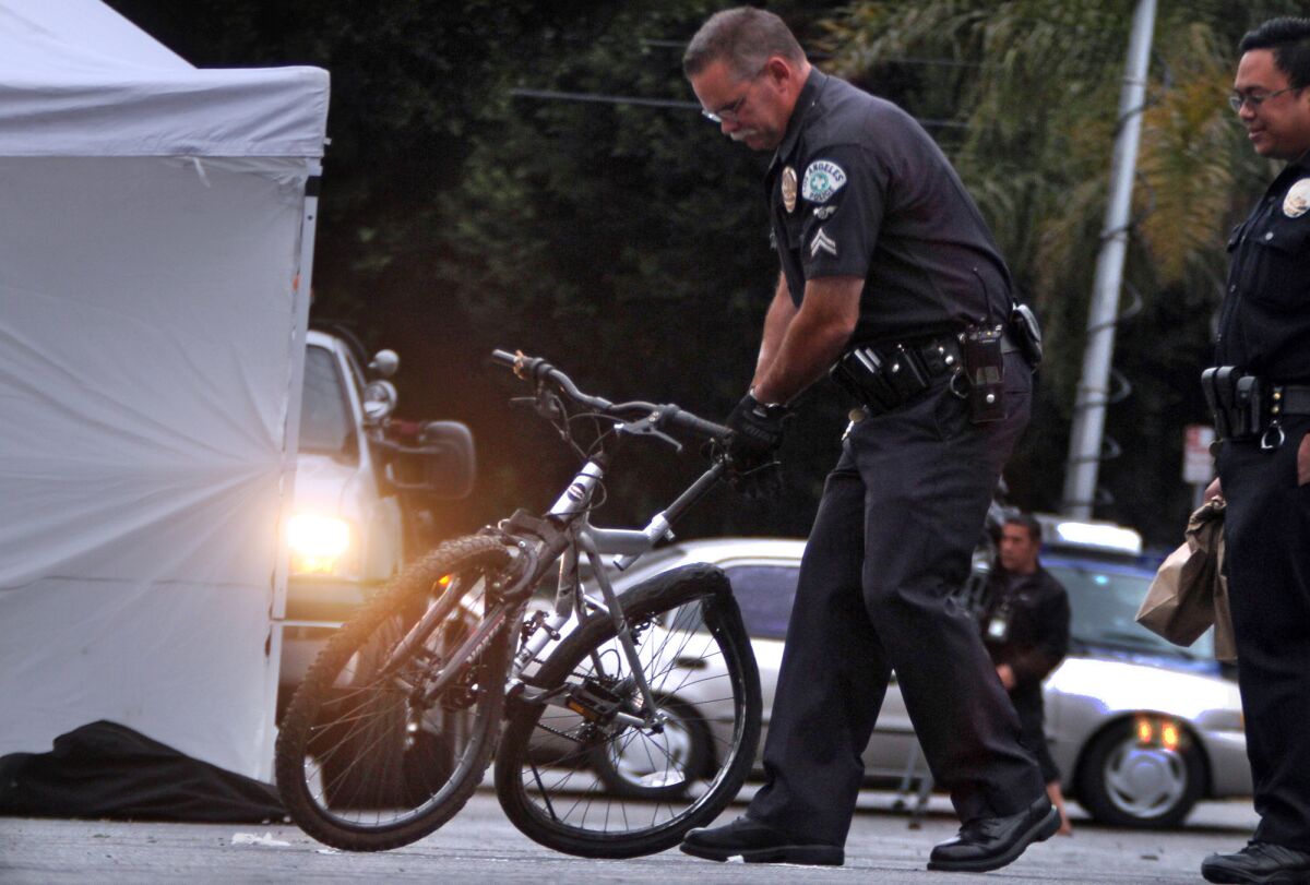 A police officer removes a bicycle whose rider was killed when he was struck by a car fleeing police after a shooting incident in Florence, authorities said.