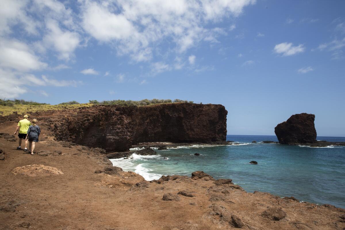 Hikers make their way toward Puu Pehe rock from Hulopoe Bay on the Hawaiian island of Lanai.