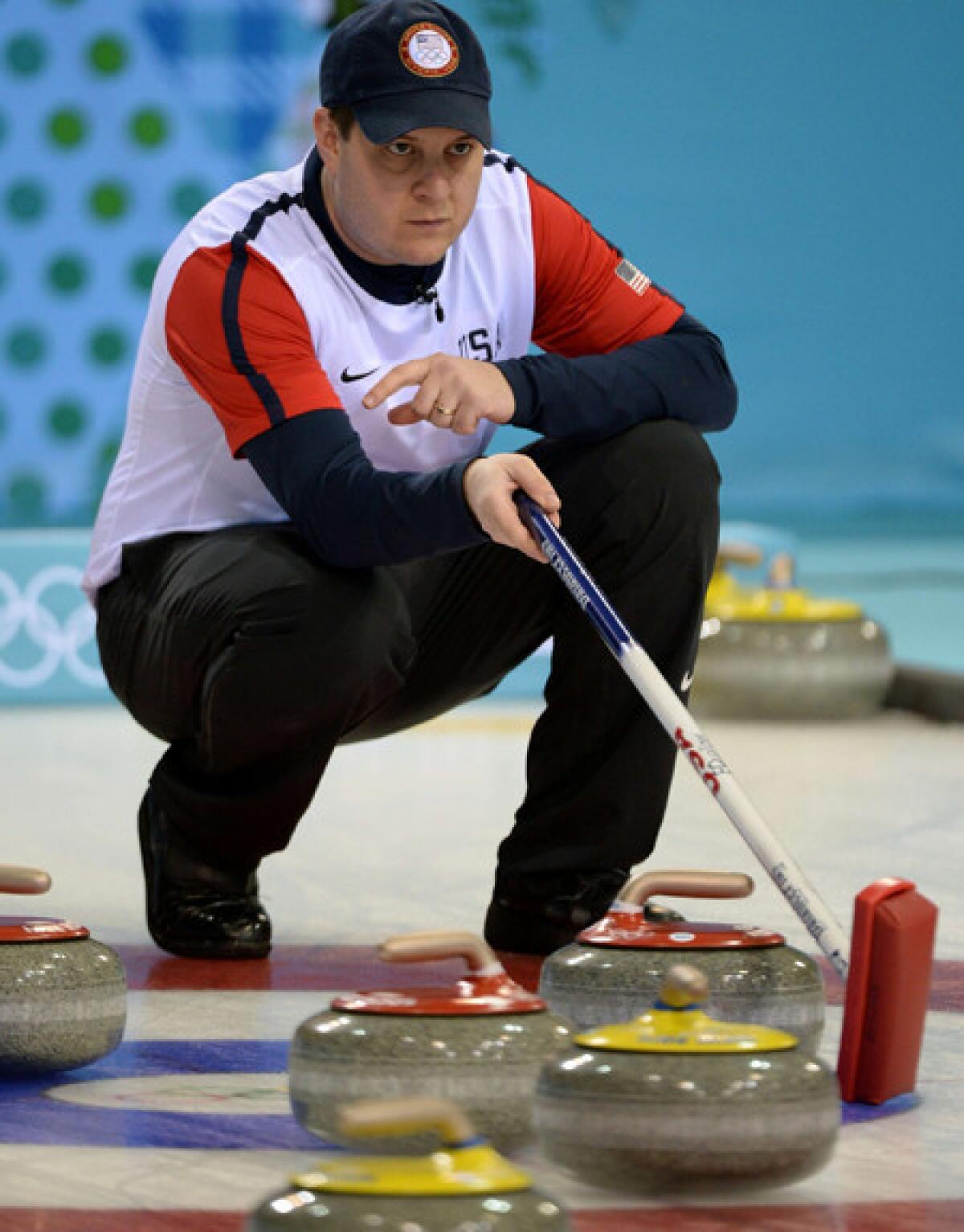 U.S. skip John Shuster checks the line of a shot during a match against Switzerland at the Sochi Olympics' Ice Cube Curling Center.