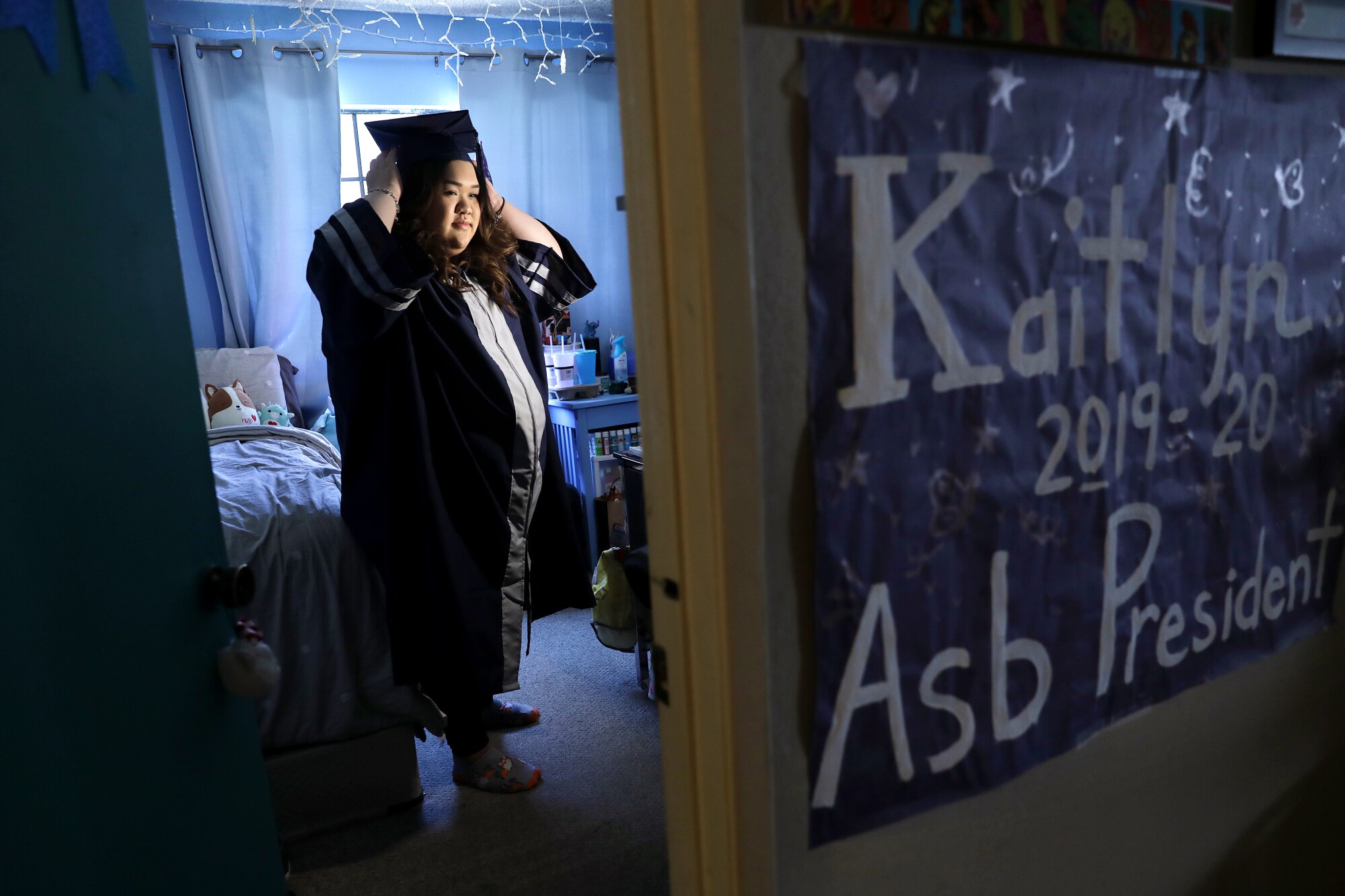 Kaitlyn Nguyen wears her graduation cap and gown at home 