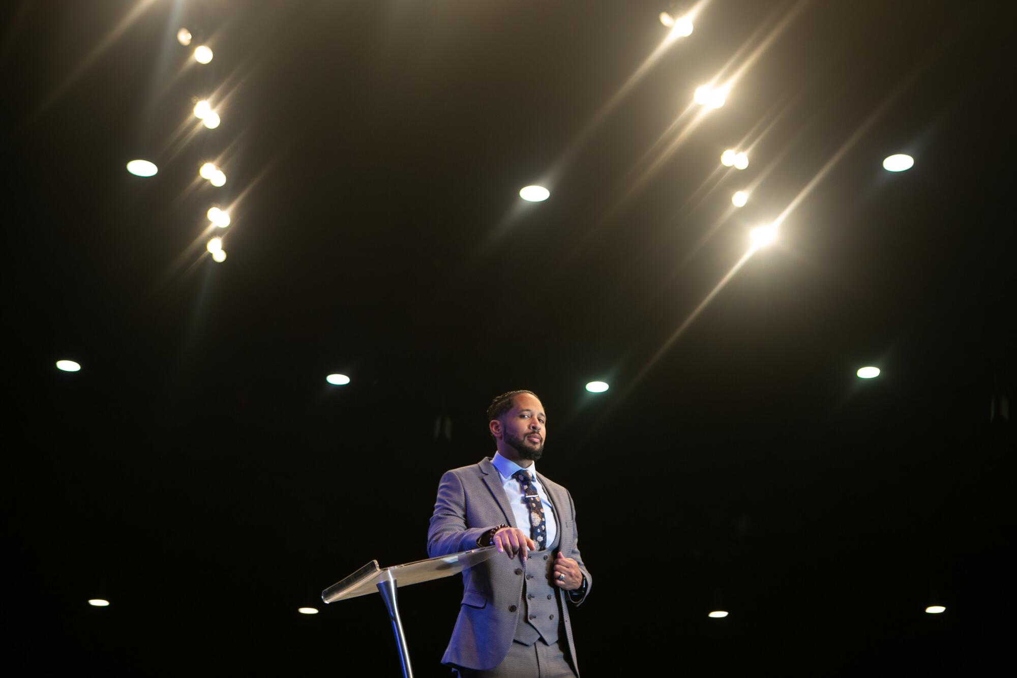 Pastor Fred Price Jr. stands under the lights of his megachurch stage