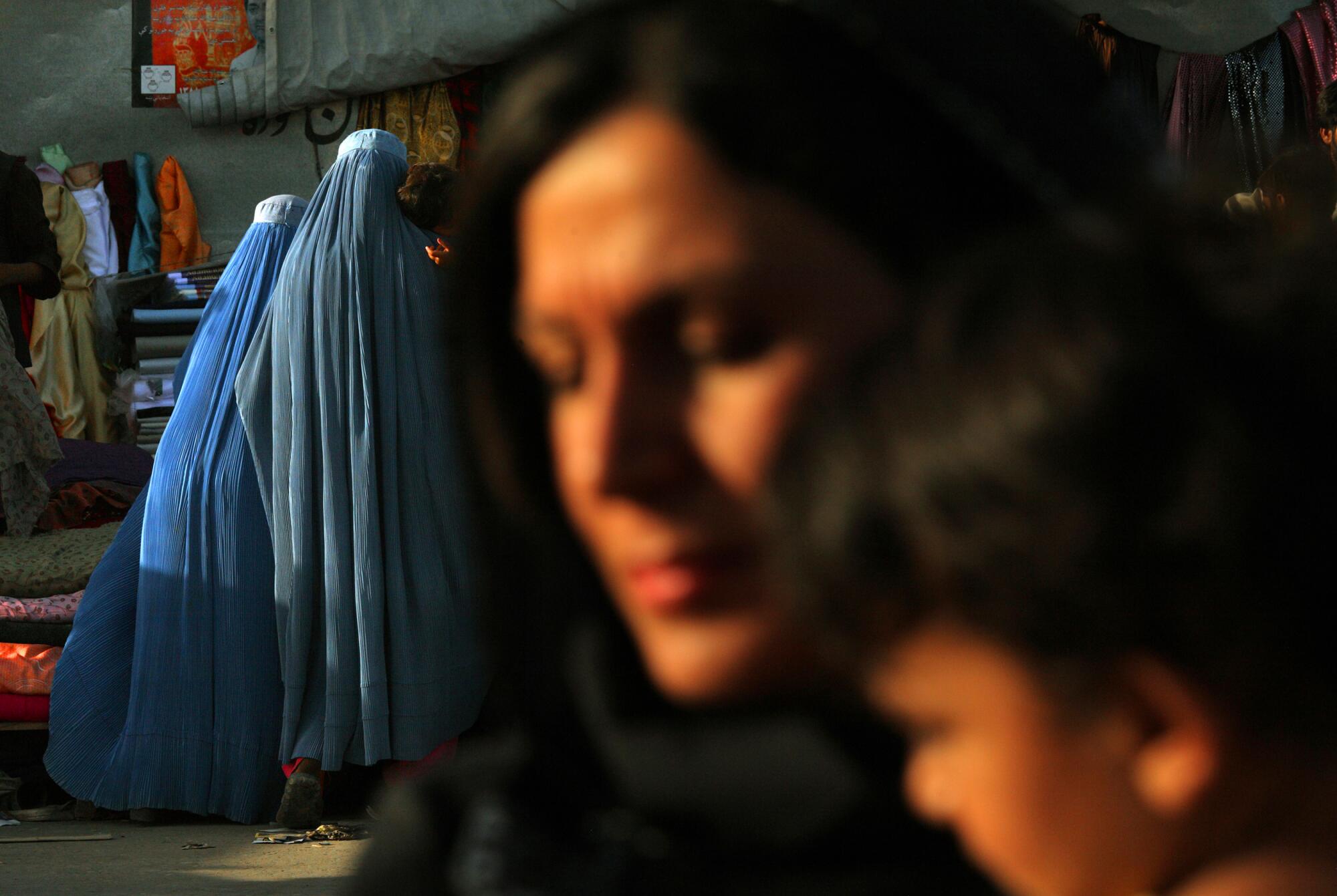 Two women in burqas walk outdoors