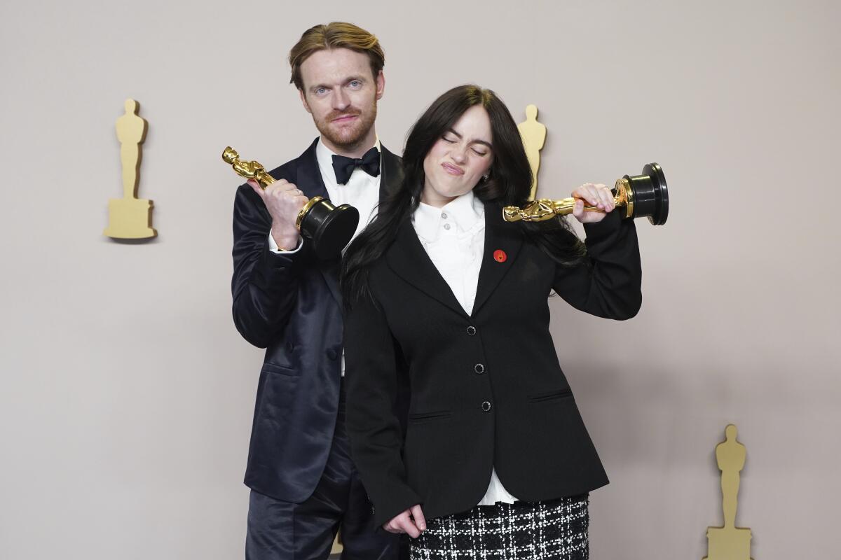 Finneas O'Connell y Billie Eilish posan en la sala de prensa con su Oscar por mejor canción original