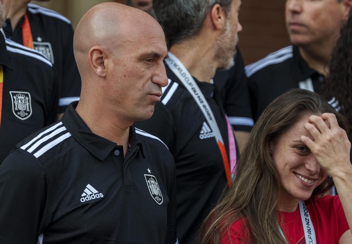 Several men in matching black and white shirts stand near a woman in a red shirt.