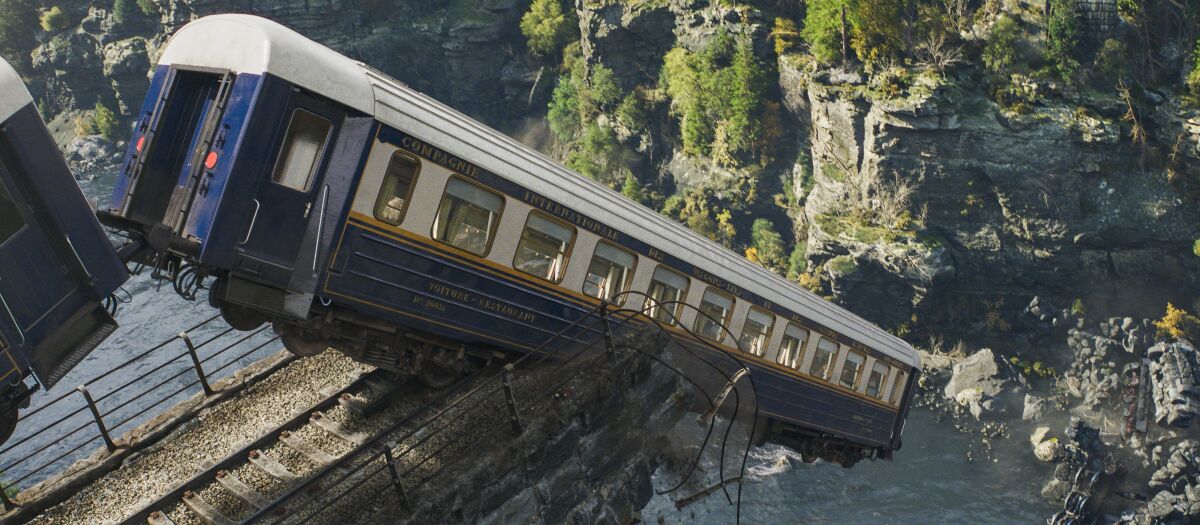 A train slowly going over the remnants of a bridge high above a gorge