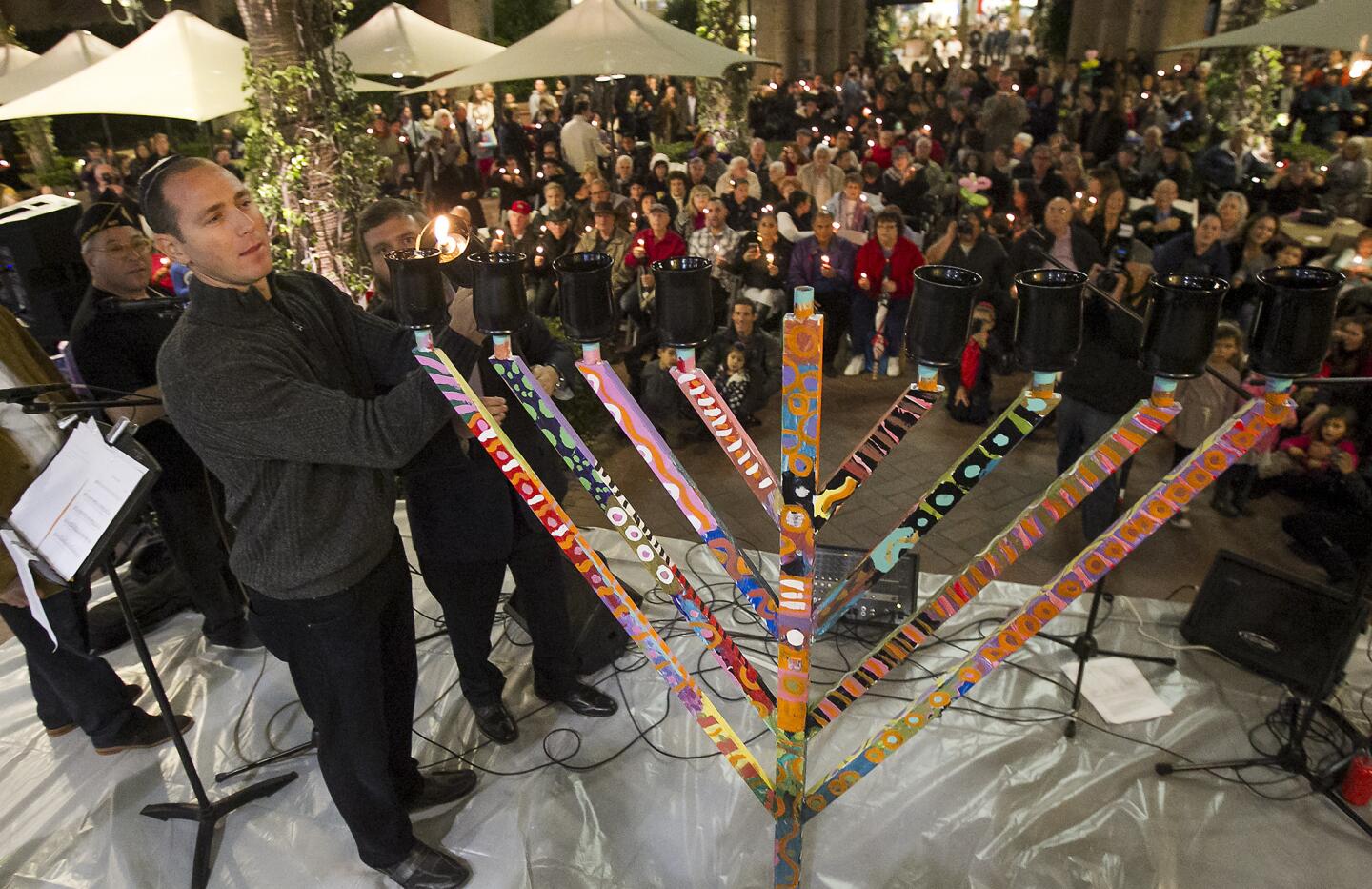 Jason Lezak, an 8-time Olympic medalist, along with Rabbi Reuven Mintz, from the Chabad Center for Jewish Life, Newport Beach, light a public menorah to celebrate the first day of Hanukkah on Tuesday, December 16, at Fashion Island.