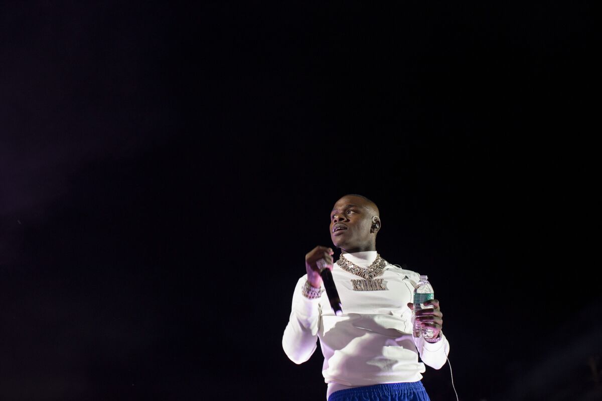 A man in a white shirt holds a microphone and a bottle of water
