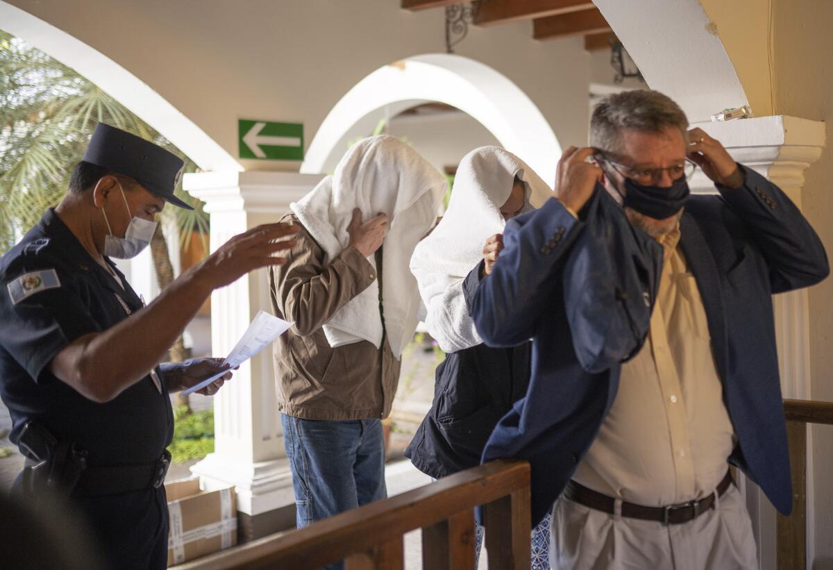 Led by their lawyer Juan Pablo Aris Bravo, right, Stephanie Allison Jolluck, and Giorgio Salvador Rossilli exit out of a courthouse with their faces covered with a towel, after they were released, in Antigua, Guatemala, Tuesday, Nov. 15, 2022. Stephanie Allison Jolluck was first captured on Nov. 9th at Guatemala City's airport when she was found to be transporting two archeological artifacts in her luggage, she was arrested and taken to a courthouse in Guatemala City and placed on probation, but then the couple was arrested on Sunday, Nov. 13, with over 150 archeological artifacts in a vehicle. (AP Photo/Santiago Billy)