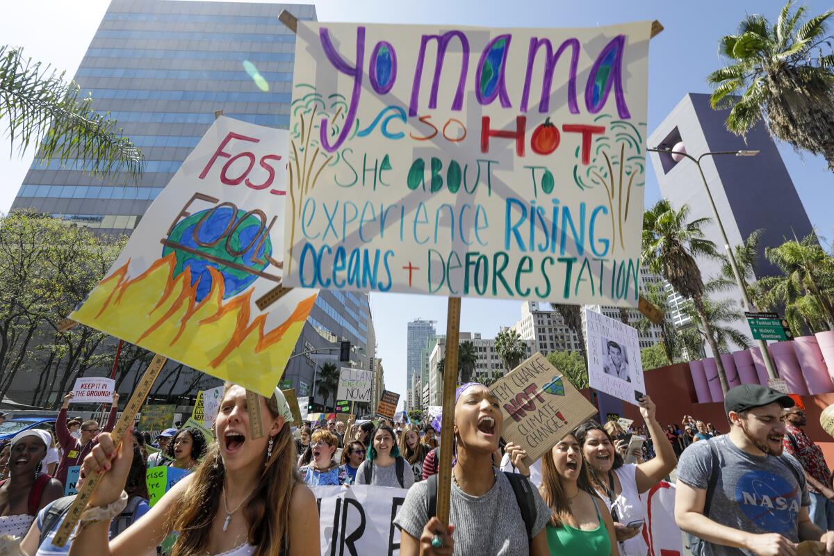 High school students take part in a rally with signs calling for climate change action.