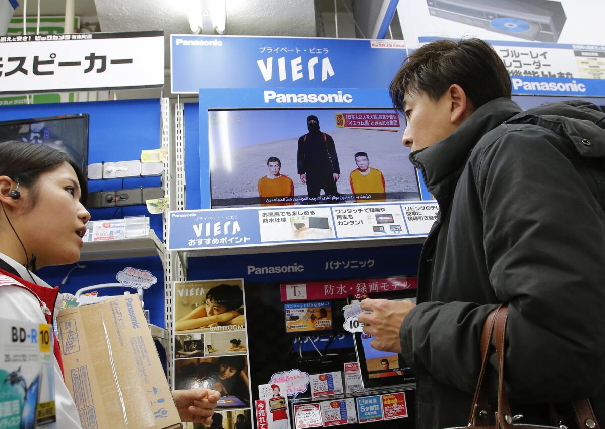 Japanese hostages held by Islamic State militants appear on a television screen in an electronics store in Tokyo on Jan. 20.