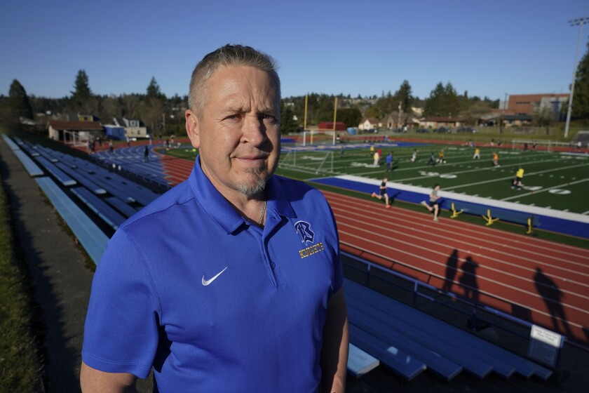 Bremerton (Wash.) assistant football coach Joe Kennedy stands next to a field.