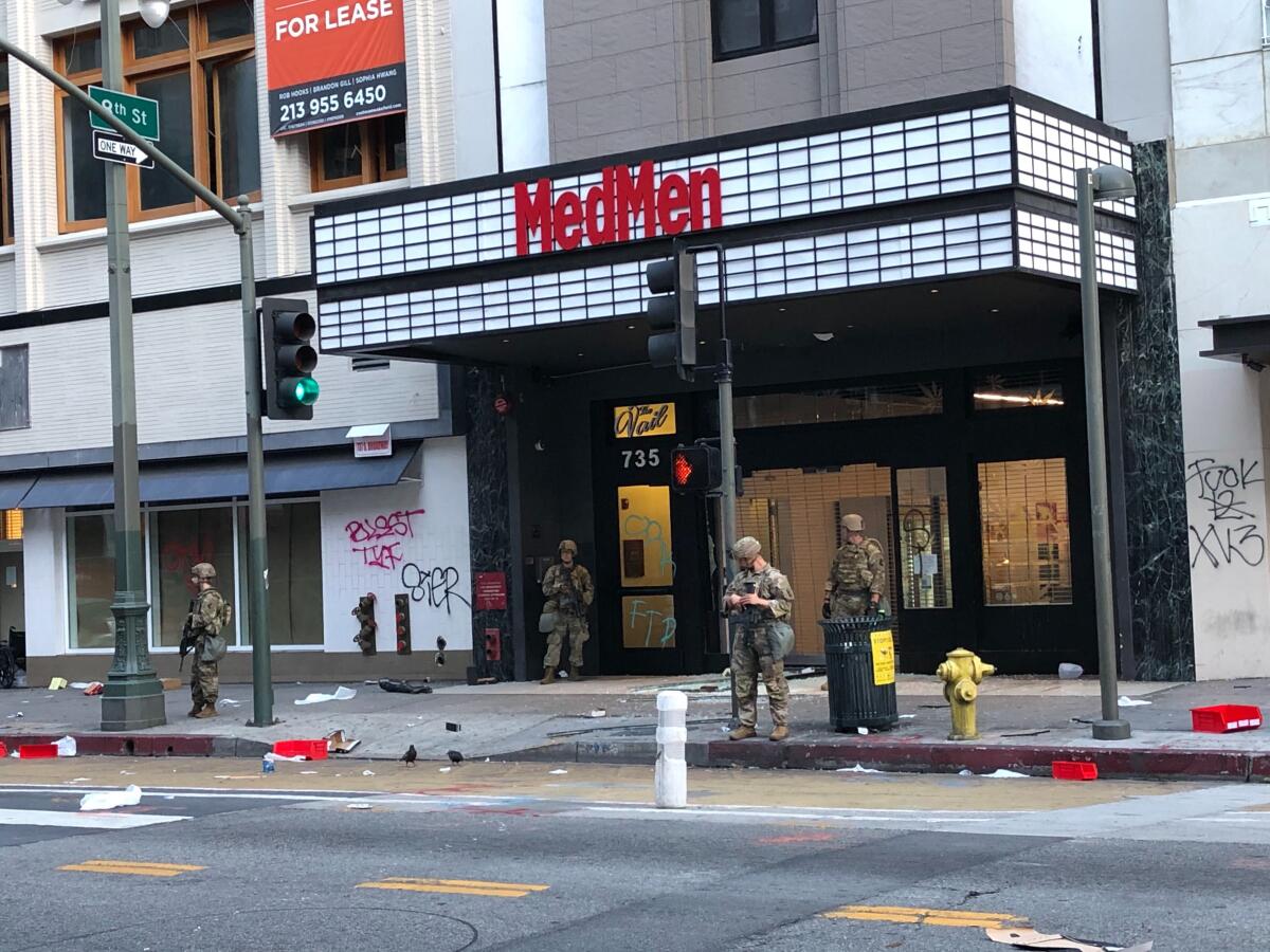 National Guardsmen stand outside shattered storefronts along Broadway in L.A.