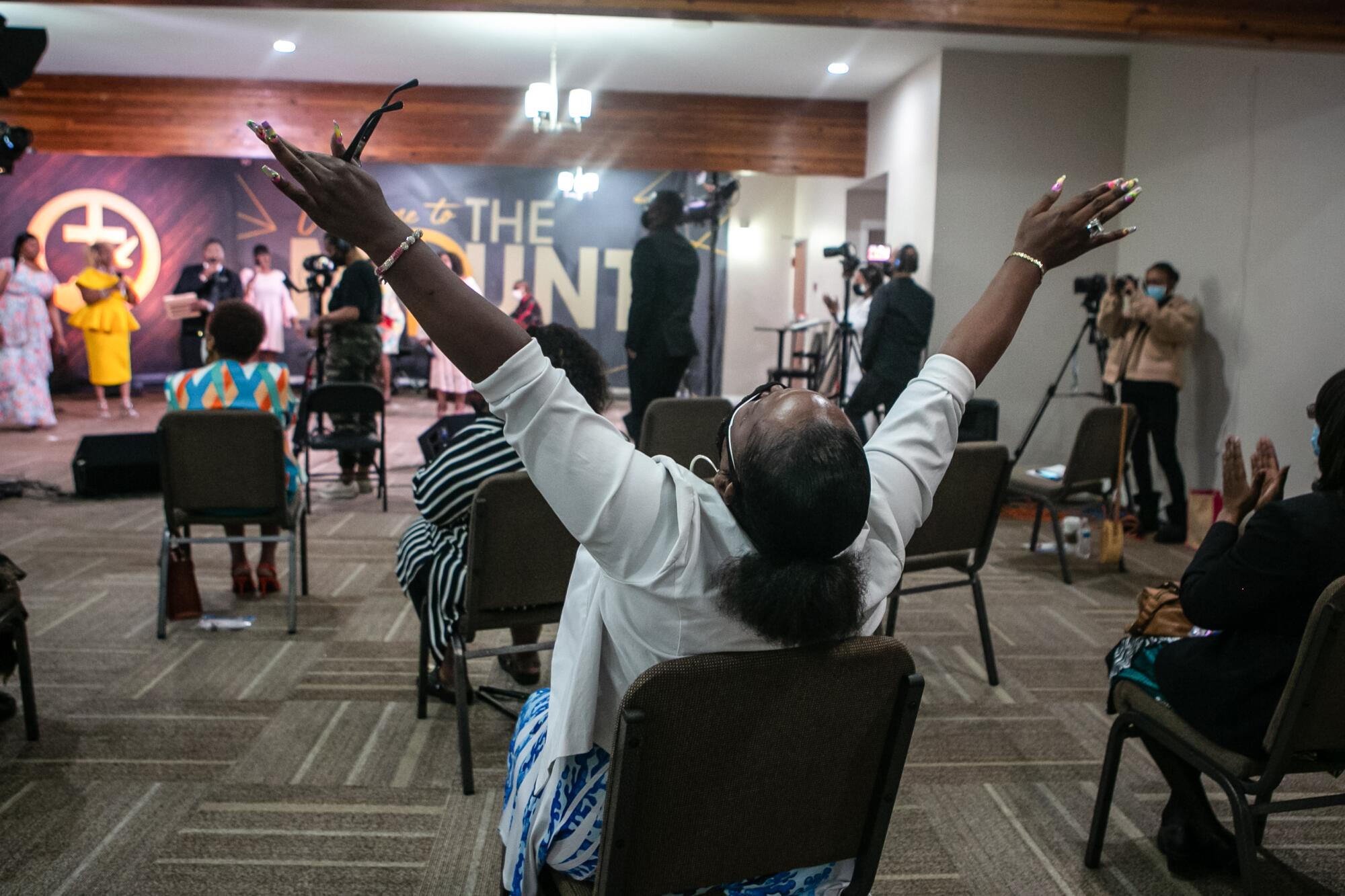 A seated woman raises her hands.