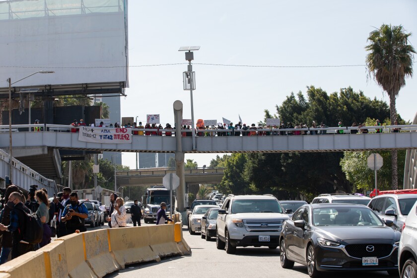 A group of protesters wait on a pedestrian bridge overlooking the port of San Ysidro 