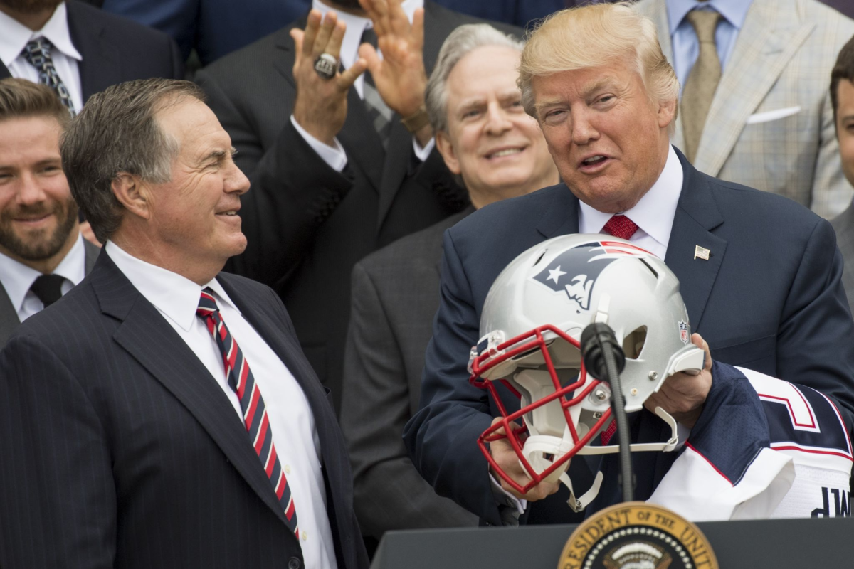 President Trump holds a football helmet given to him by the New England Patriots head coach Bill Belichick.