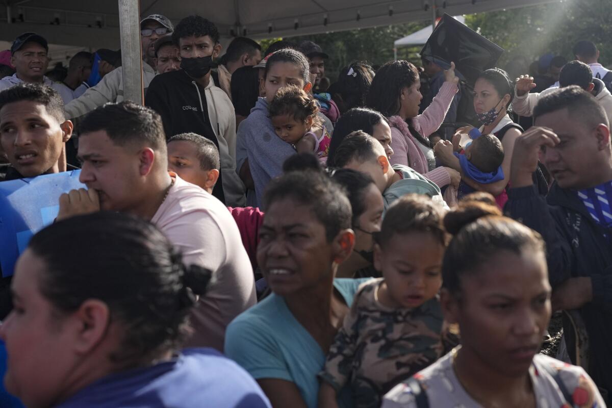 Venezuelan migrants and their children wait to enter a temporary migrant shelter