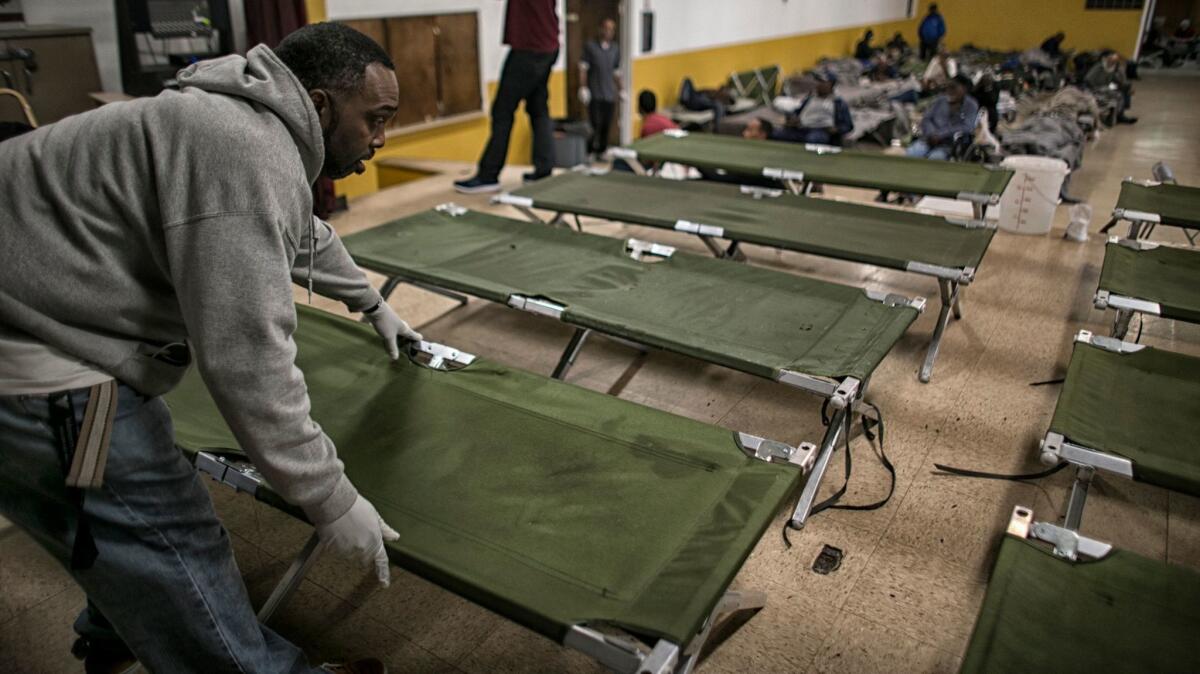 Jeffrey Robinson unfolds dozens of cots at a winter homeless shelter in March at Bethel AME Church in South Los Angeles.