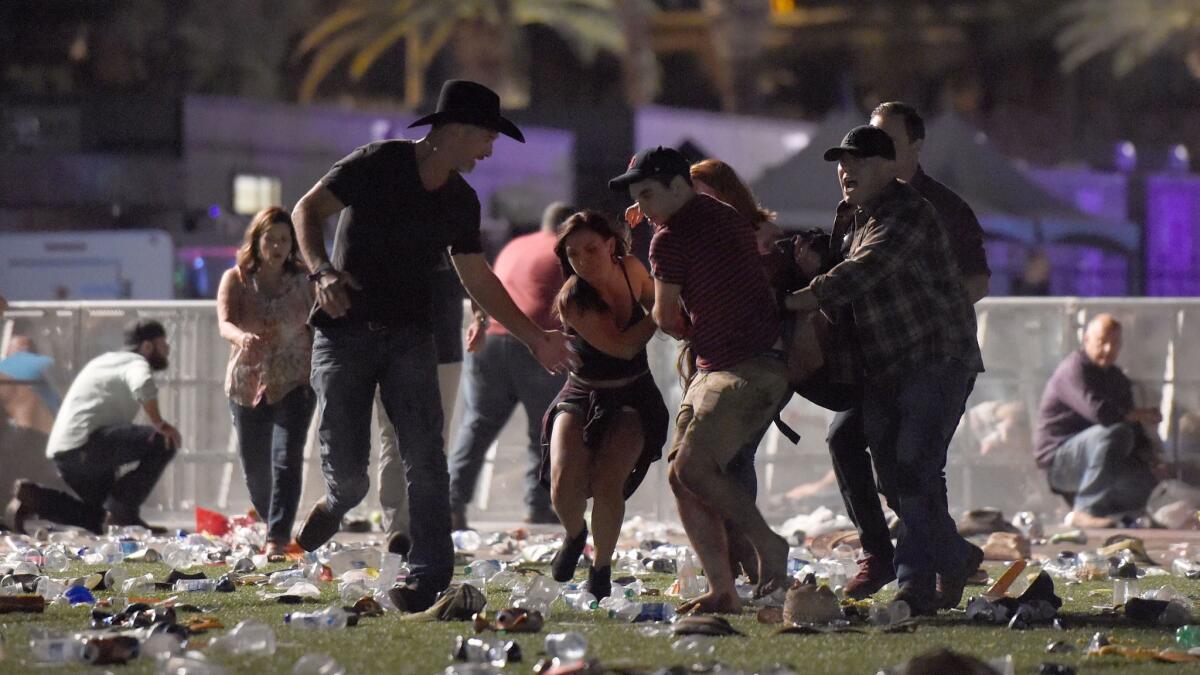 Concertgoers at the Route 91 Harvest country music festival in Las Vegas carry an injured person.
