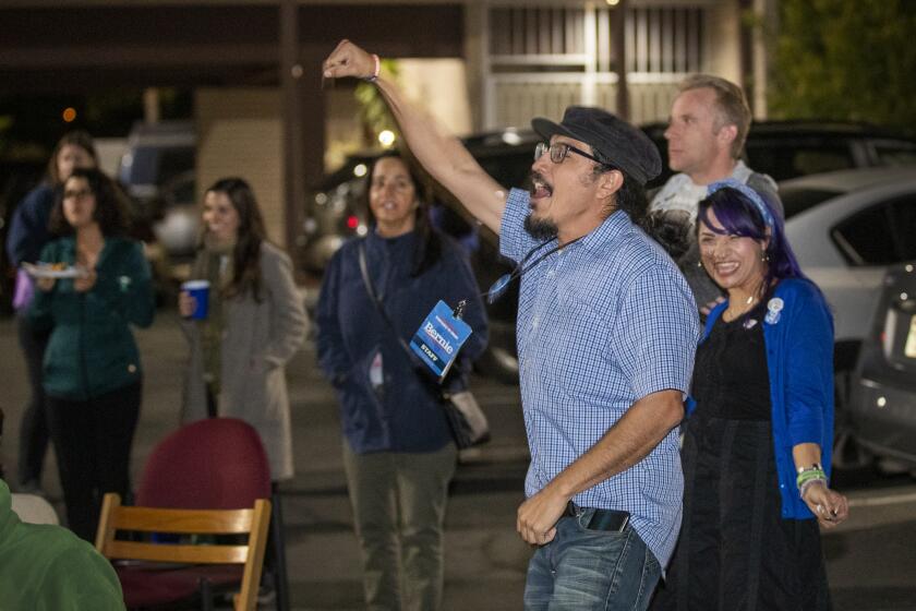 SANTA ANA, CALIF. -- TUESDAY, MARCH 3, 2020: Joese Hernandez, center in blue shirt, longtime community activist from Santa Ana, rallies with Bernie Sanders campaign volunteers celebrating the news that Bernie Sanders is projected as the winner of California at a Super Tuesday election night party at the Bernie Sanders campaign headquarters in Santa Ana, Calif., on March 3, 2020. (Allen J. Schaben / Los Angeles Times)