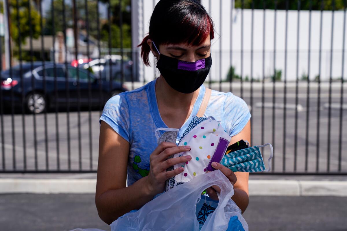 Eileen DenAdel of Culver City holds masks she made in the parking lot of the Costume Designers Guild on April 3 in Burbank.