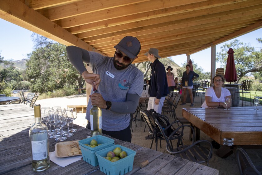 A man opens a bottle of white wine.