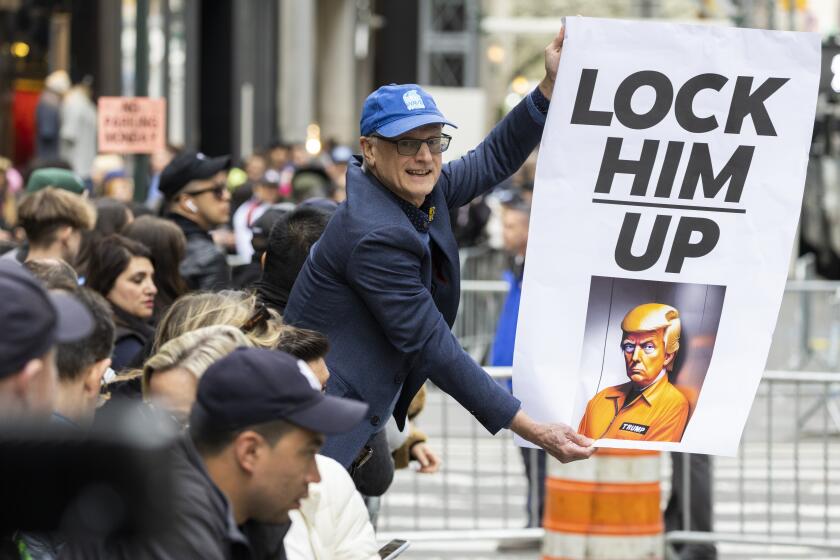 A protester holds a placard outside Trump Tower in New York on Monday, April 3, 2023. Former President Donald Trump is expected to be booked and arraigned on Tuesday on charges arising from hush money payments during his 2016 campaign. (AP Photo/Corey Sipkin)