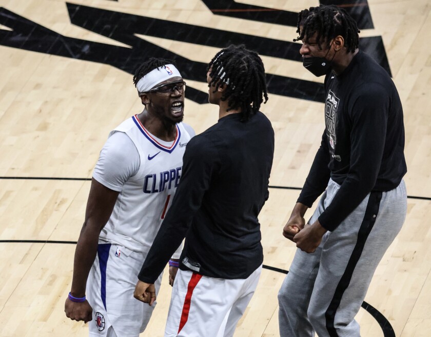 Clippers guard Reggie Jackson, left, celebrates with teammates Terance Mann, center, and Daniel Oturu.