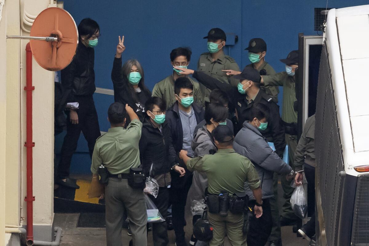 Former lawmaker Leung Kwok-hung, known as "Long Hair," second left, shows a victory sign and some of the 47 pro-democracy activists are escorted by Correctional Services officers to a prison van in Hong Kong, Thursday, March 4, 2021. A marathon court hearing for 47 pro-democracy activists in Hong Kong charged with conspiracy to commit subversion enters its fourth day on Thursday, as the court deliberates over whether the defendants will be granted bail. (AP Photo/Kin Cheung)