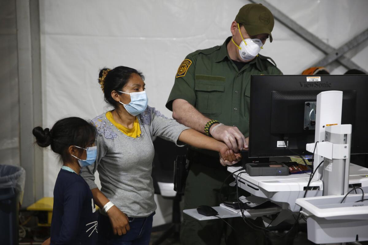 A migrant and her daughter have their biometric data entered at a holding facility in the Rio Grande Valley, Texas.