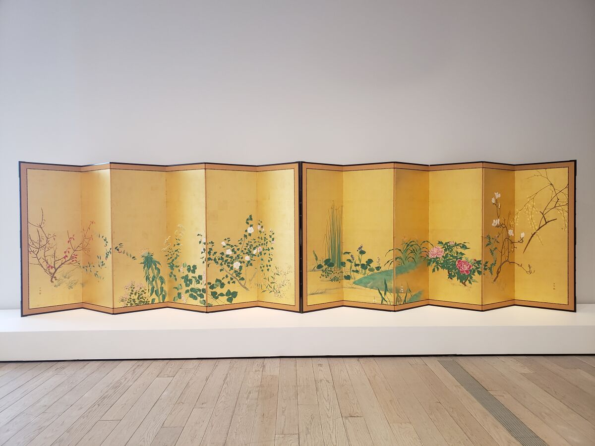 Ein goldener Bildschirm, der mit Blumen bemalt ist.