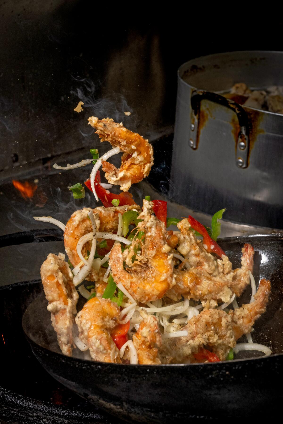 Des crevettes salées et poivrées sont jetées dans un wok chez Sophy's : Cambodge Town Food & Music, le 11 mars 2024 à Long Beach 