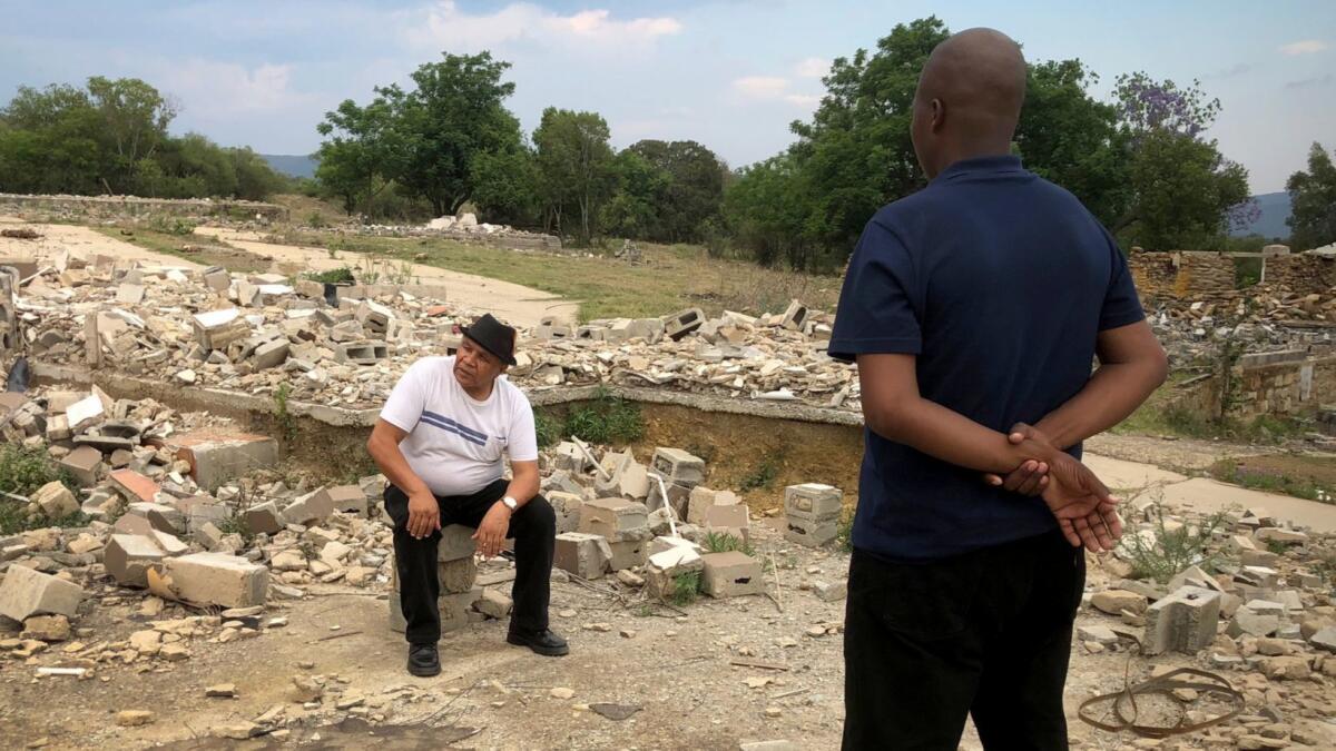 Raymond Trollip, seated, chair of the Uthukela District Land Reform Committee, surveys the rubble of a factory that used to employ hundreds of people in his area before tensions over a land transfer caused it to close.