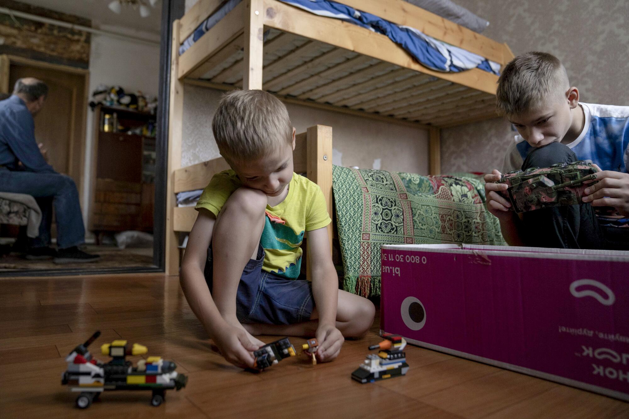 Two boys play with toys in a room.