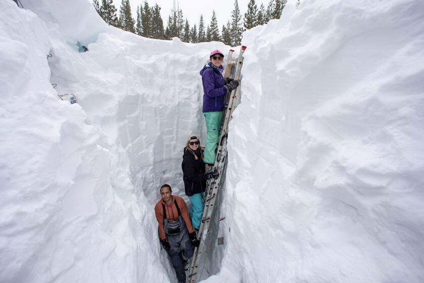 Working inside a nearly 18-foot-deep snow pit at the UC Berkeley Central Sierra Snow Lab, from left, Shaun Joseph, Claudia Norman, Helena Middleton take measurements of snow temperatures ahead of a weather storm on March 9, 2023, in Soda Springs, Calif. The more than 55 feet of snow that a dozen storms have dumped on the mountains along the Nevada-California line this season has etched its way into the history books as the second snowiest on record at the Central Sierra Snow Lab. (Karl Mondon/Bay Area News Group via AP)