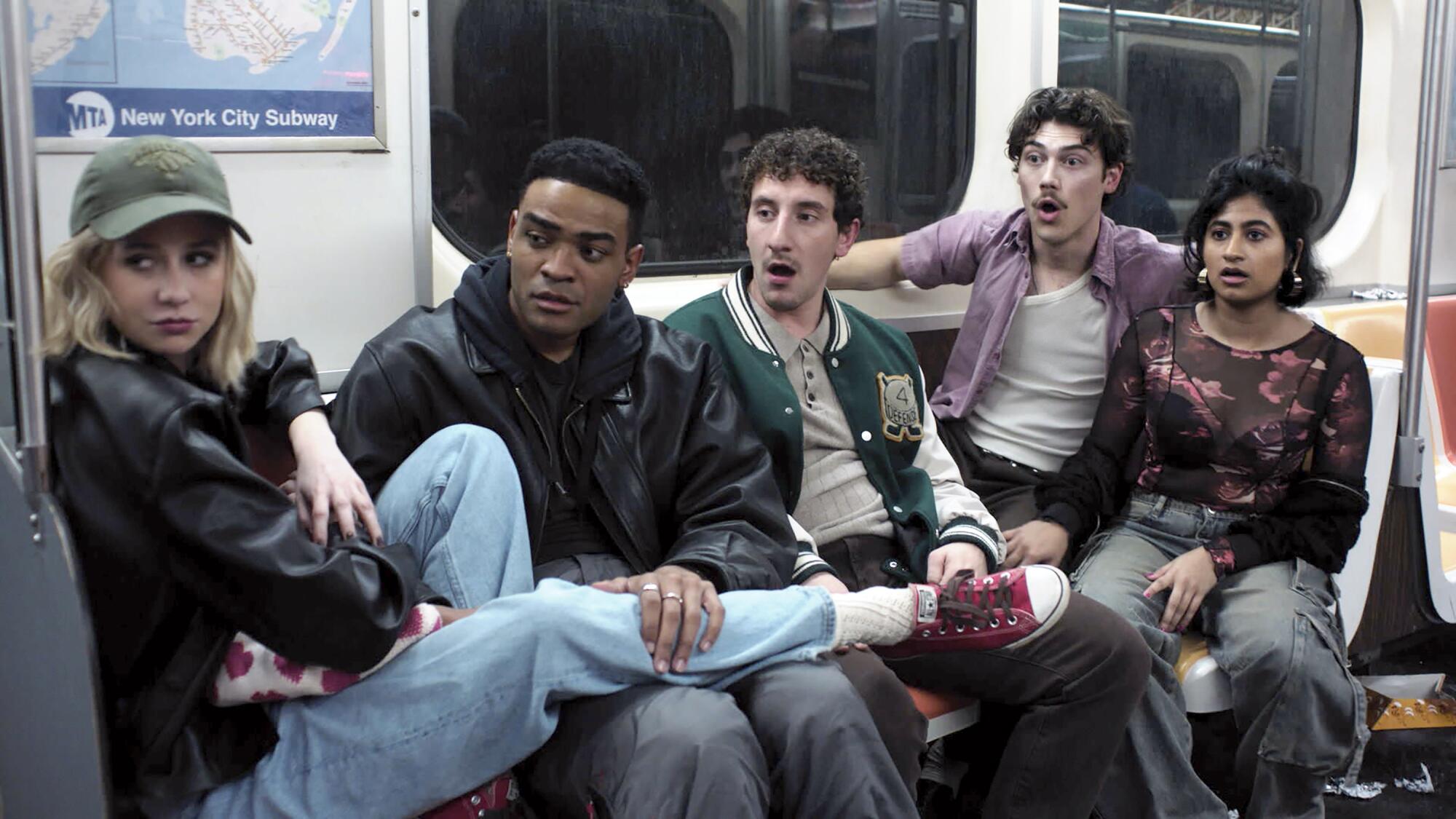 Five people sitting on subway benches looking surprised at something out of frame.