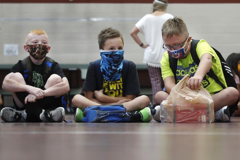 Tres estudiantes de primaria portando mascarillas para evitar la propagación de COVID19 esperan a que comiencen las clases en Godley, Texas, el miércoles 5 de agosto de 2020. Tres distritos escolares rurales en el condado de Johnson estuvieron entre los primeros en Texas en regresar a clases presenciales. (FotoAP/LM Otero)